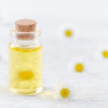 a bottle of chamomile oil with fresh chamomile flowers
